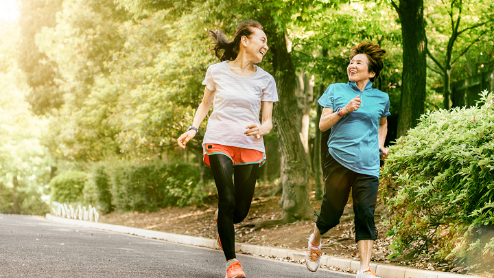 Two older women running through a park