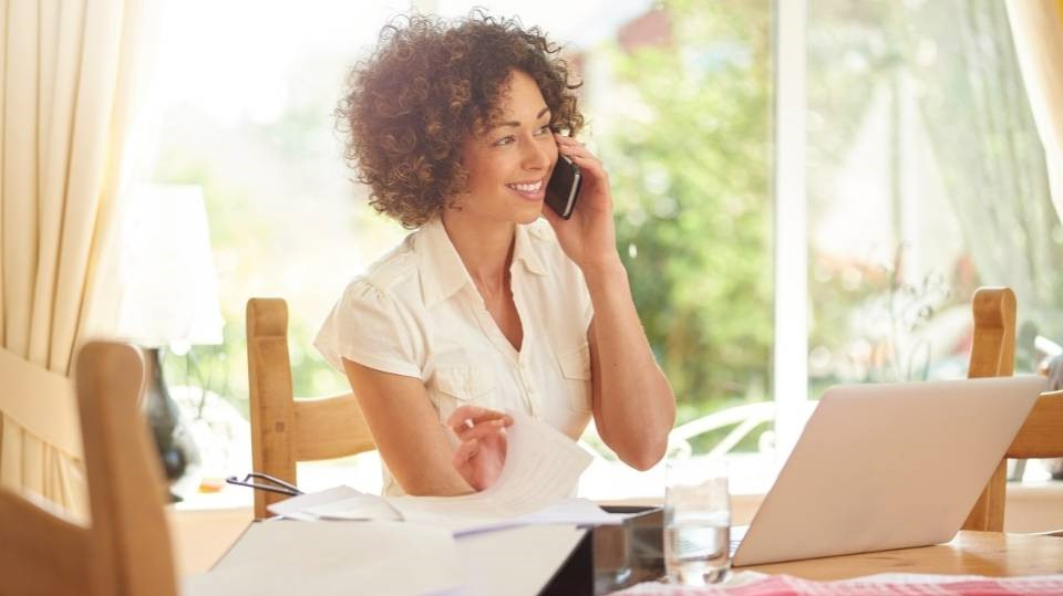 Woman smiling and talking on the phone at home