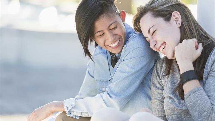 Young couple sitting outdoors laughing together