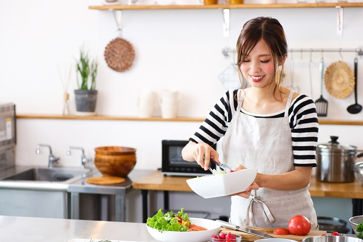 Woman smiling while preparing a salad in the kitchen