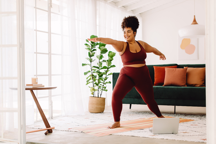 Healthy woman exercising at home watching online video on laptop