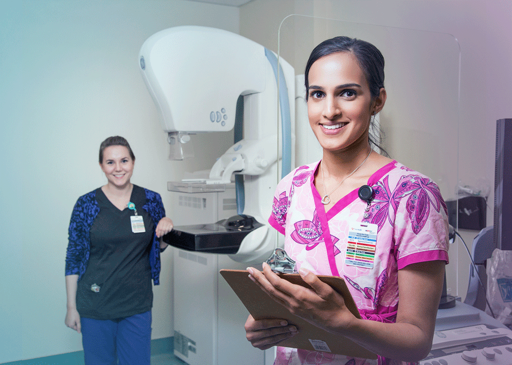 Technologists stand in front of mammography machine