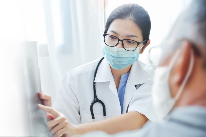 Doctor wearing eyeglasses and mask giving advice to patient in medical room