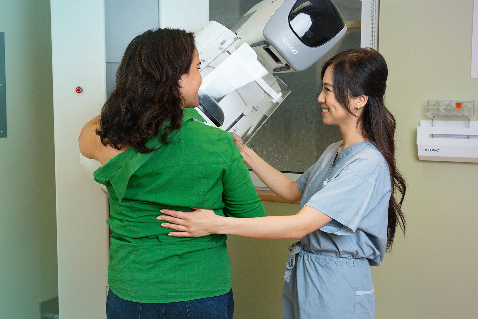 A woman being helped by a medical professional as she gets a mammogram