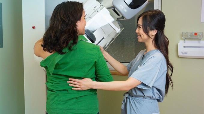 Two Medical radiation technologists (MRTs) stand with mammography equipment