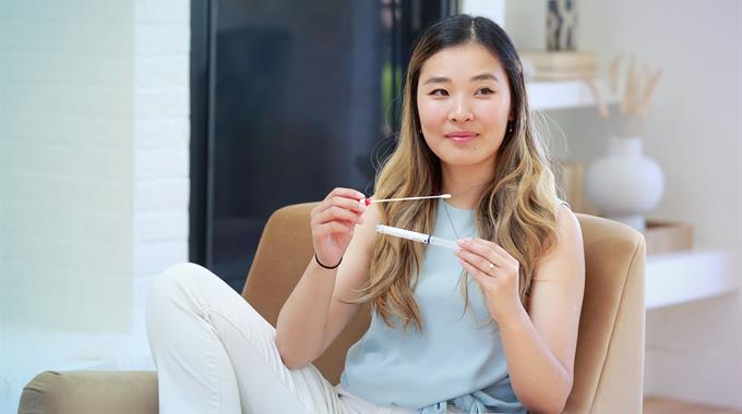 Woman sitting on a chair holding a cervix self-screening kit 