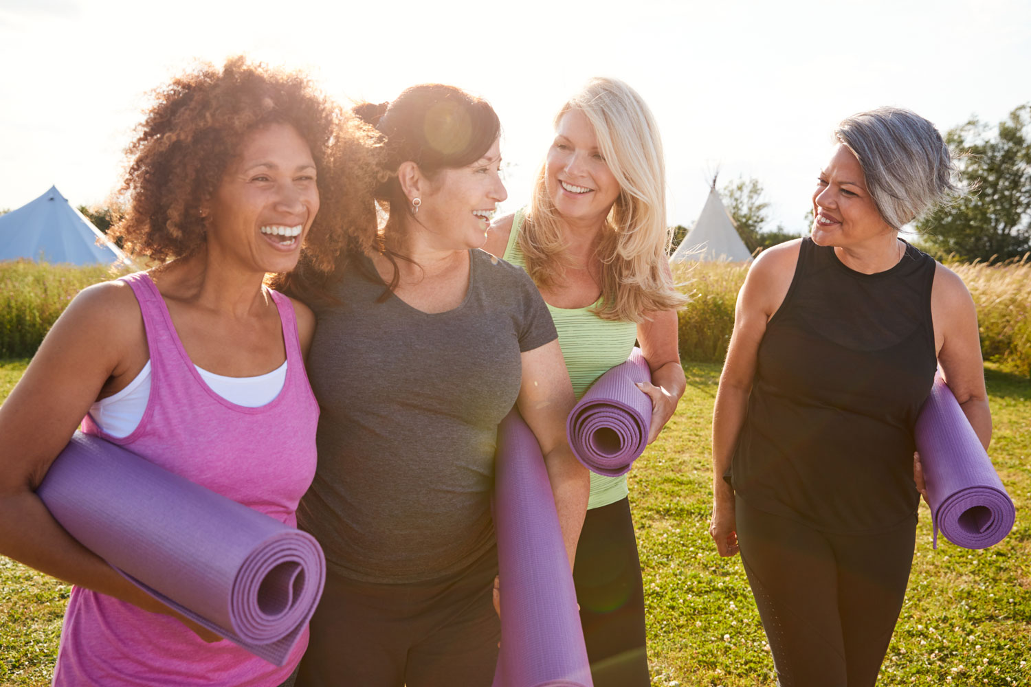 Women walking outside carrying yoga mats 