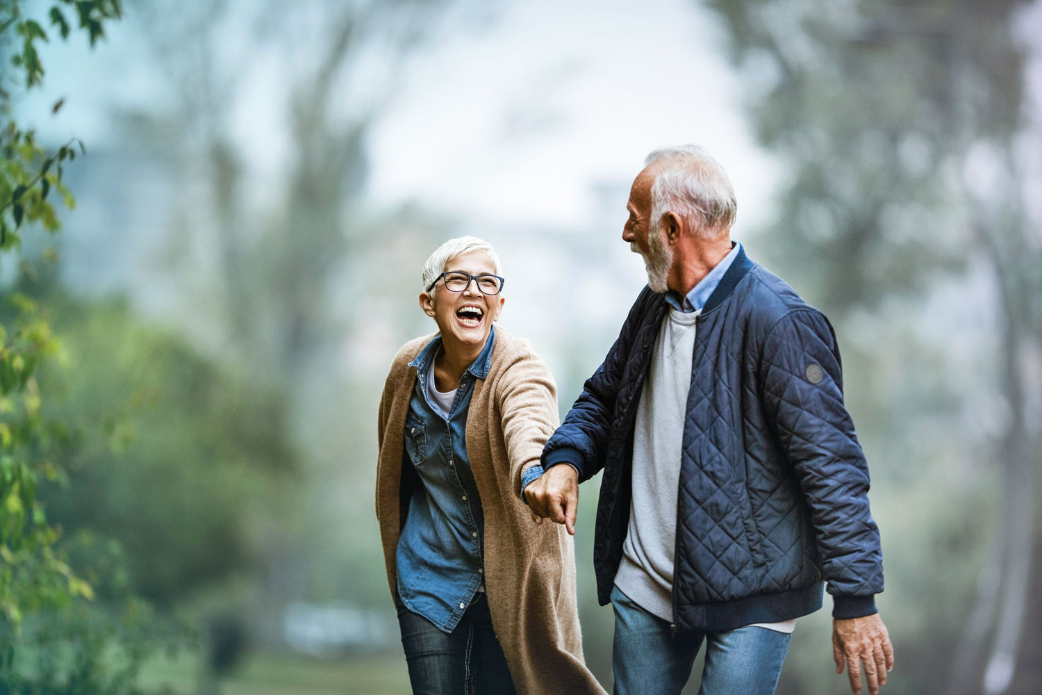 Couple holding hands walking in the woods