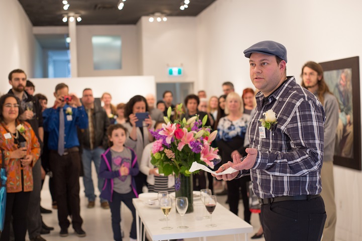Man gives speech to audience in art gallery