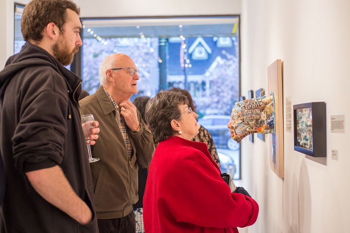 People examining sculpture of a head at art gallery