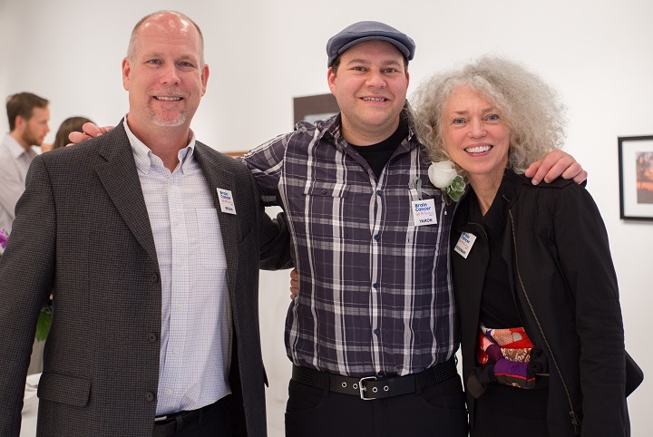Three smiling people pose for camera at art gallery