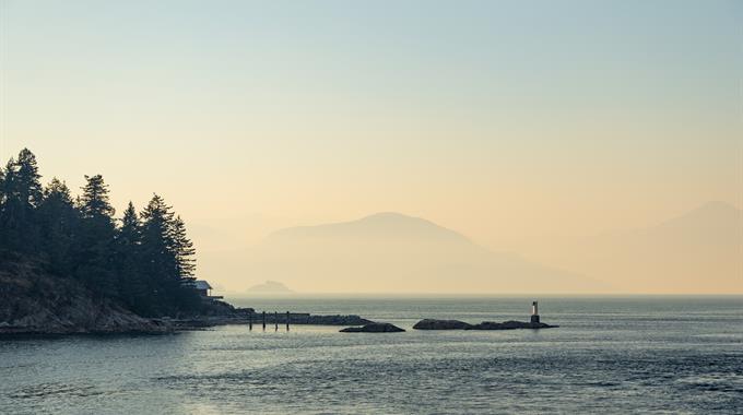 Hazy skies blanket the landscape and ocean off the coast of British Columbia from wildfire smoke