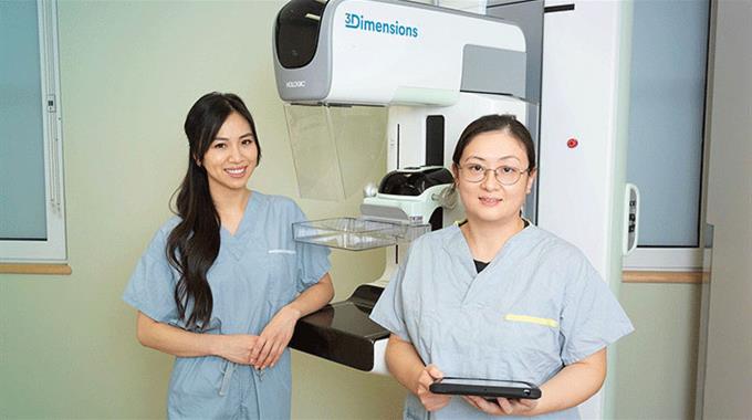 Two MRTs posing with mammography equipment