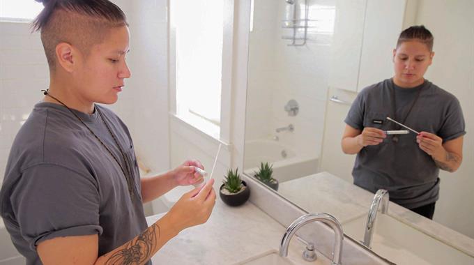 Person stands in bathroom looking at the cervix self-screening swab