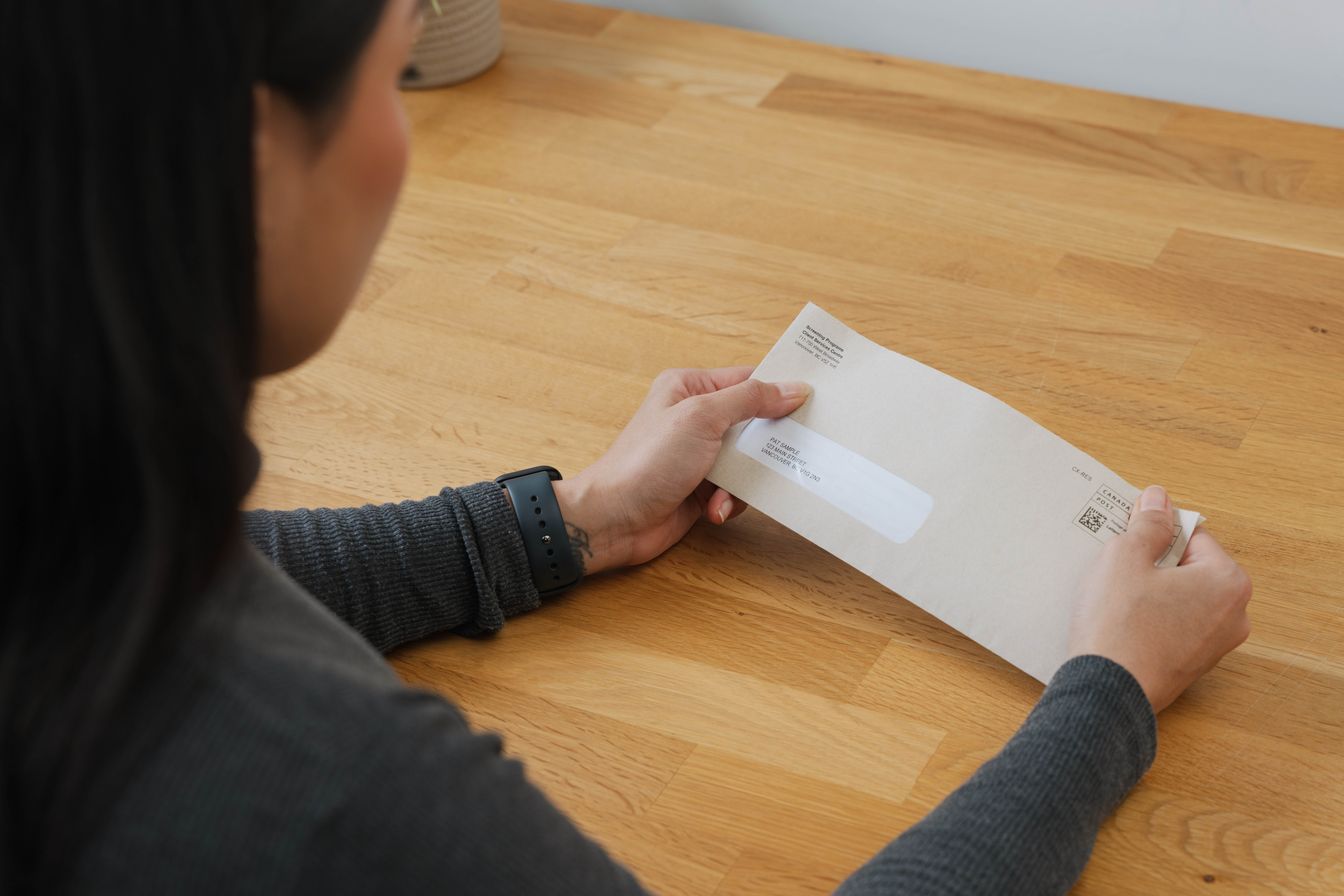 Woman looking at phone with computer in front of her