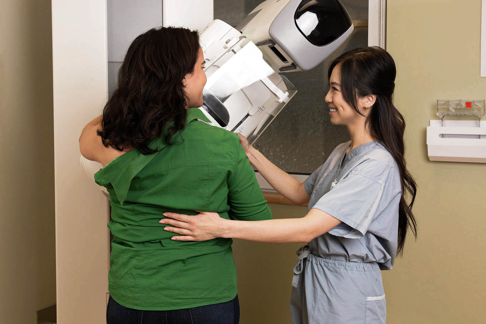 A woman being helped by a medical professional as she gets a mammogram
