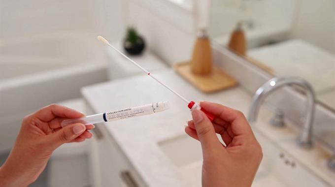Hands holding swab in bathroom