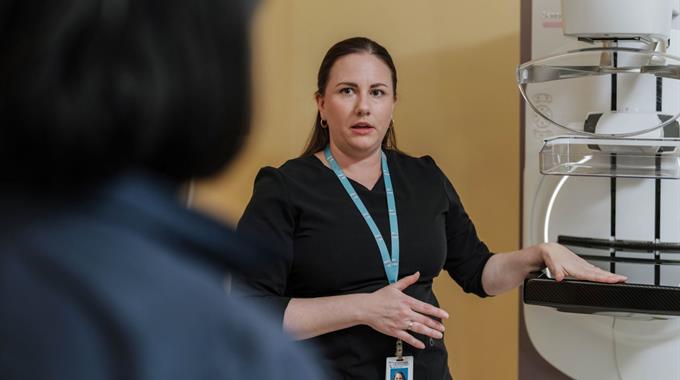 Technologist talks to patient with mammogram machine 