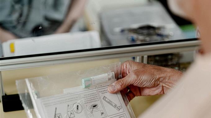 A person holds a FIT test received through window at Lab