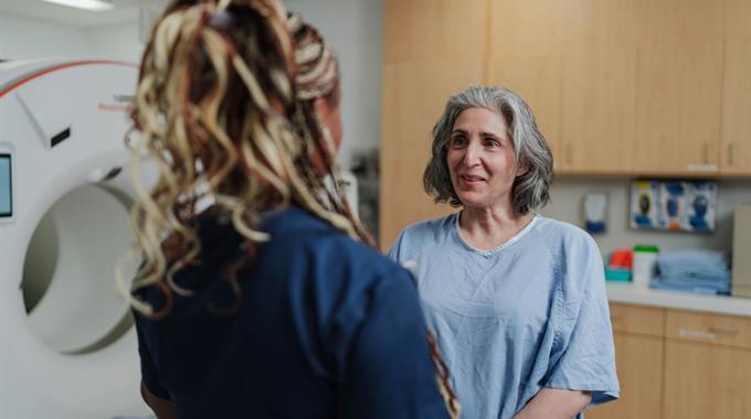 Technologist talking to patient in front of CT scanner
